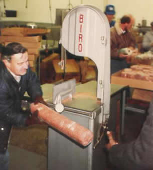 Ralph a longtime church member and volunteer use the meat saw to cut 10 pound rolls of frozen hamburger into smaller portions for the Grocery Shelf.